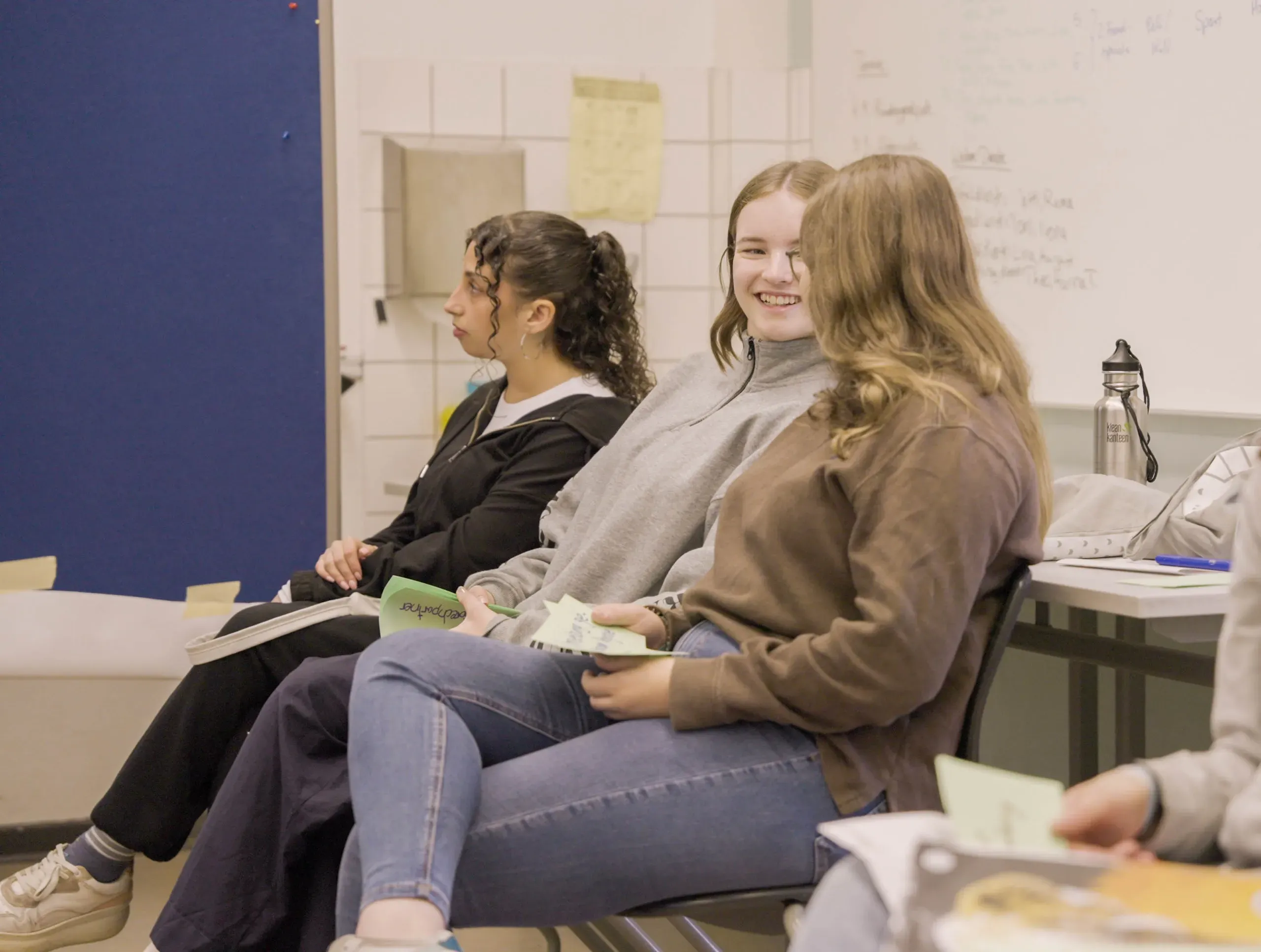Jugendliche sitzen im Klassenzimmer, unterhalten sich und lachen