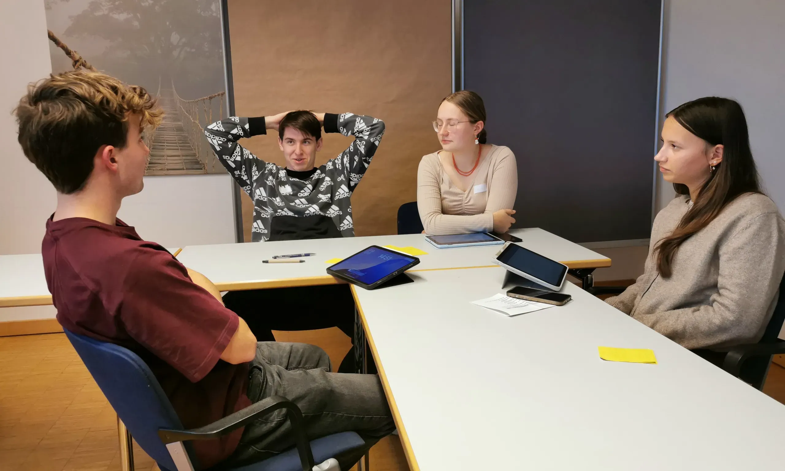 Vier Jugendliche sitzen am Tisch und unterhalten sich.