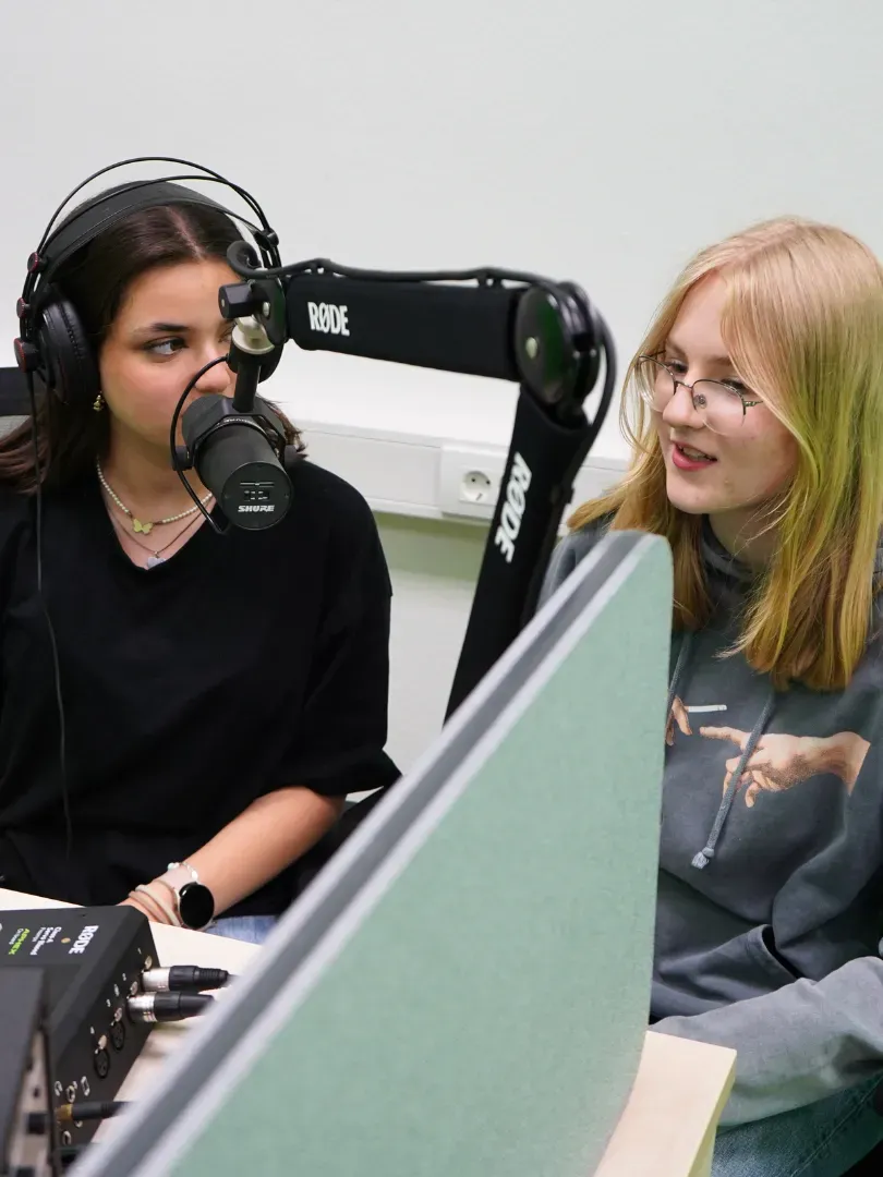 Zwei Jugendliche in einem Studio nehmen einen Podcast auf